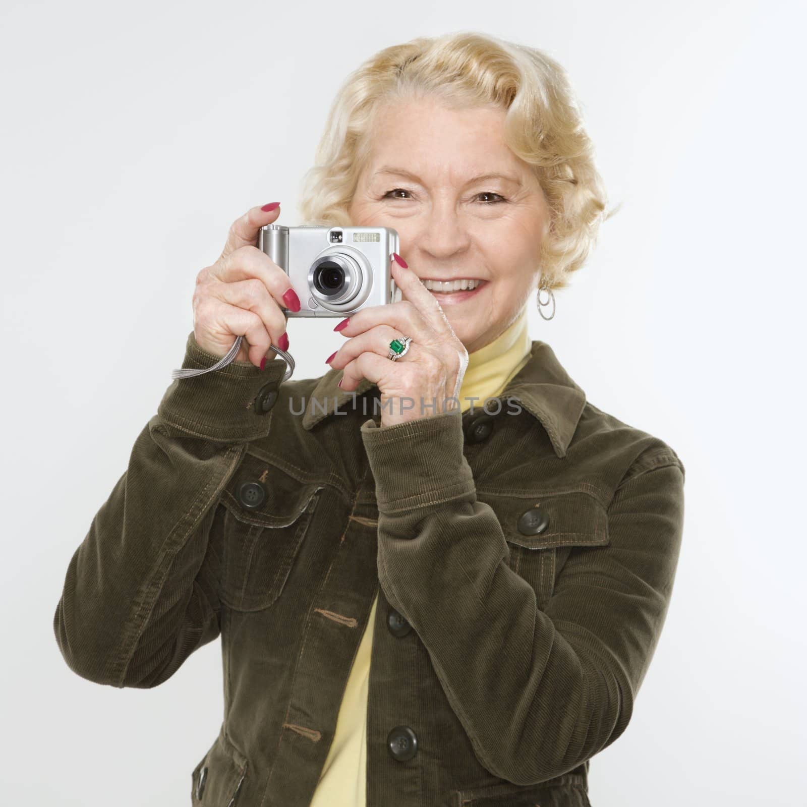 Caucasian senior woman taking photo with digital camera of viewer.