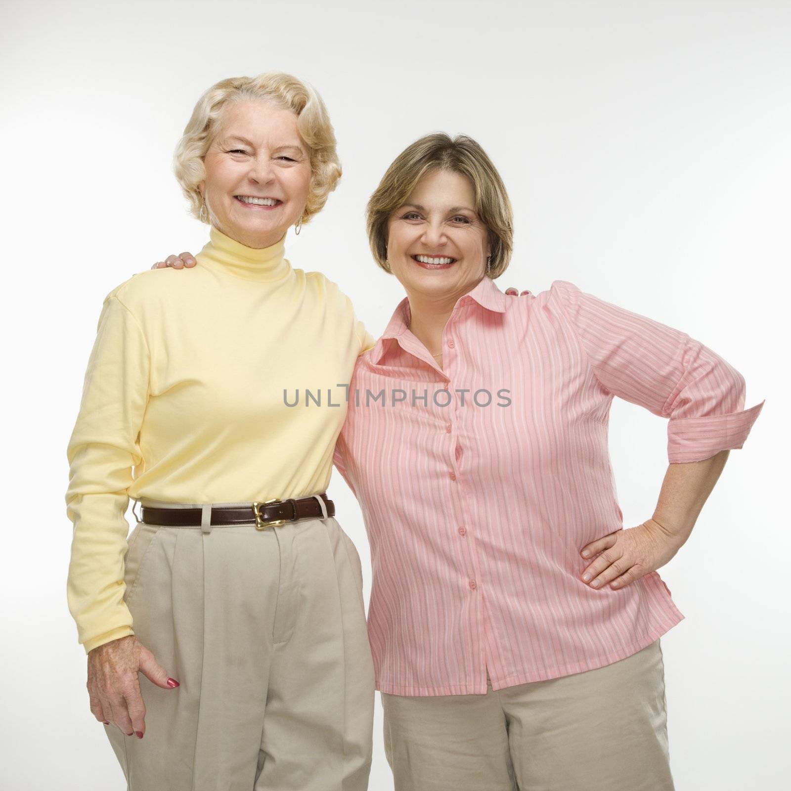 Caucasian senior woman and middle aged woman smiling with arms around each other.