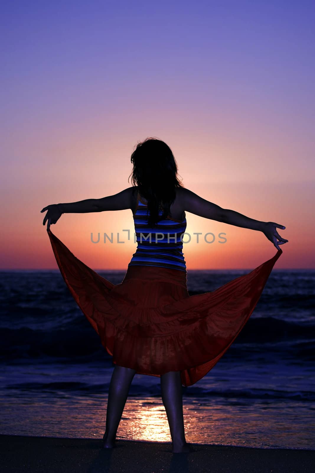 Woman holding the skirt at the sunset
