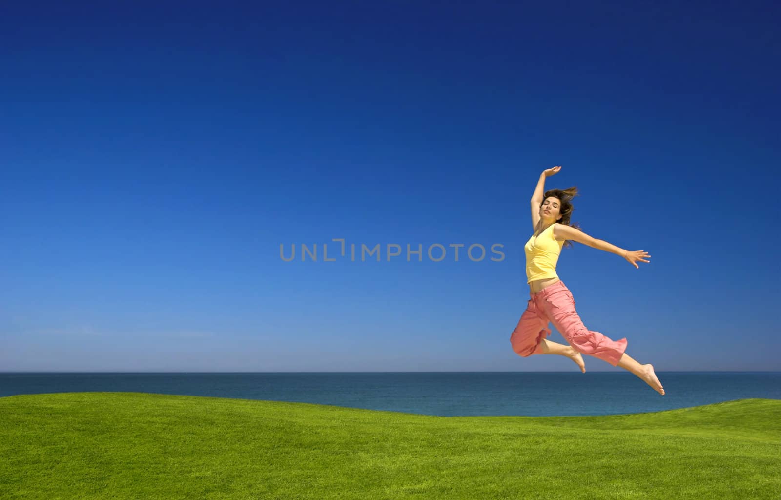 Beautiful woman jumping on a green field