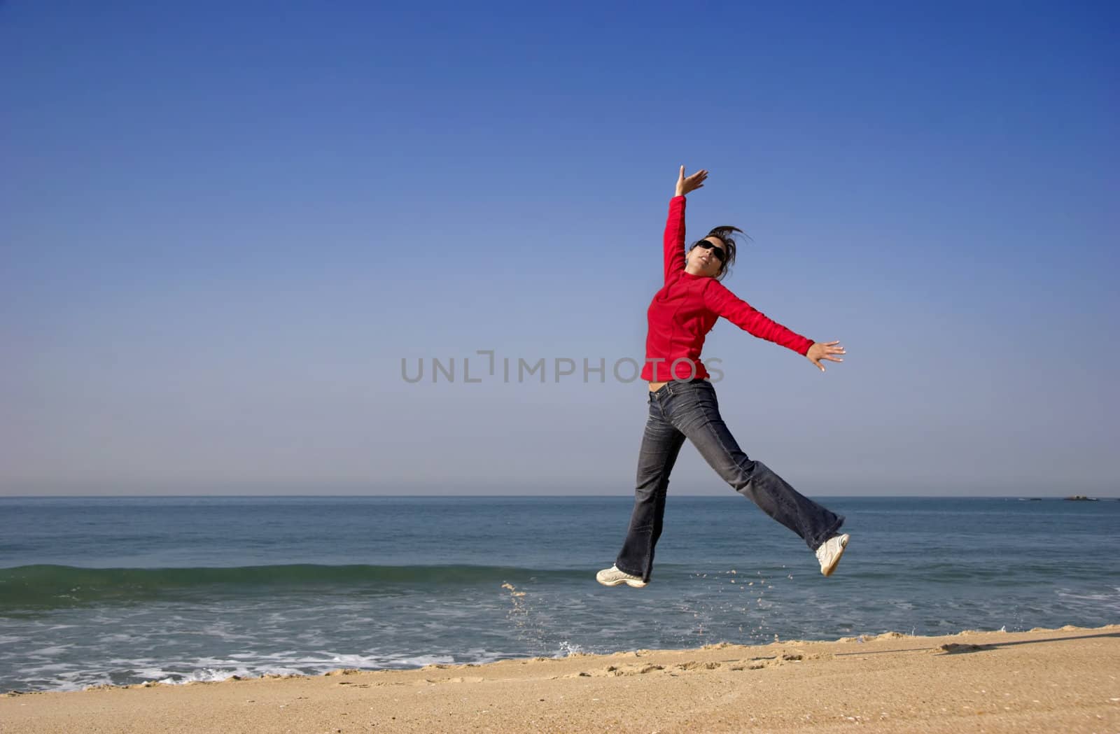 Young woman jumping for fun in a beautiful beach