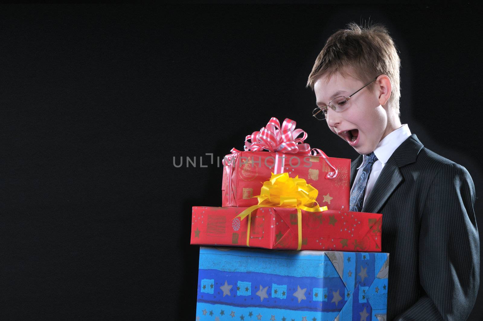 boy in a dark suit gets on the hip bright boxes with gifts