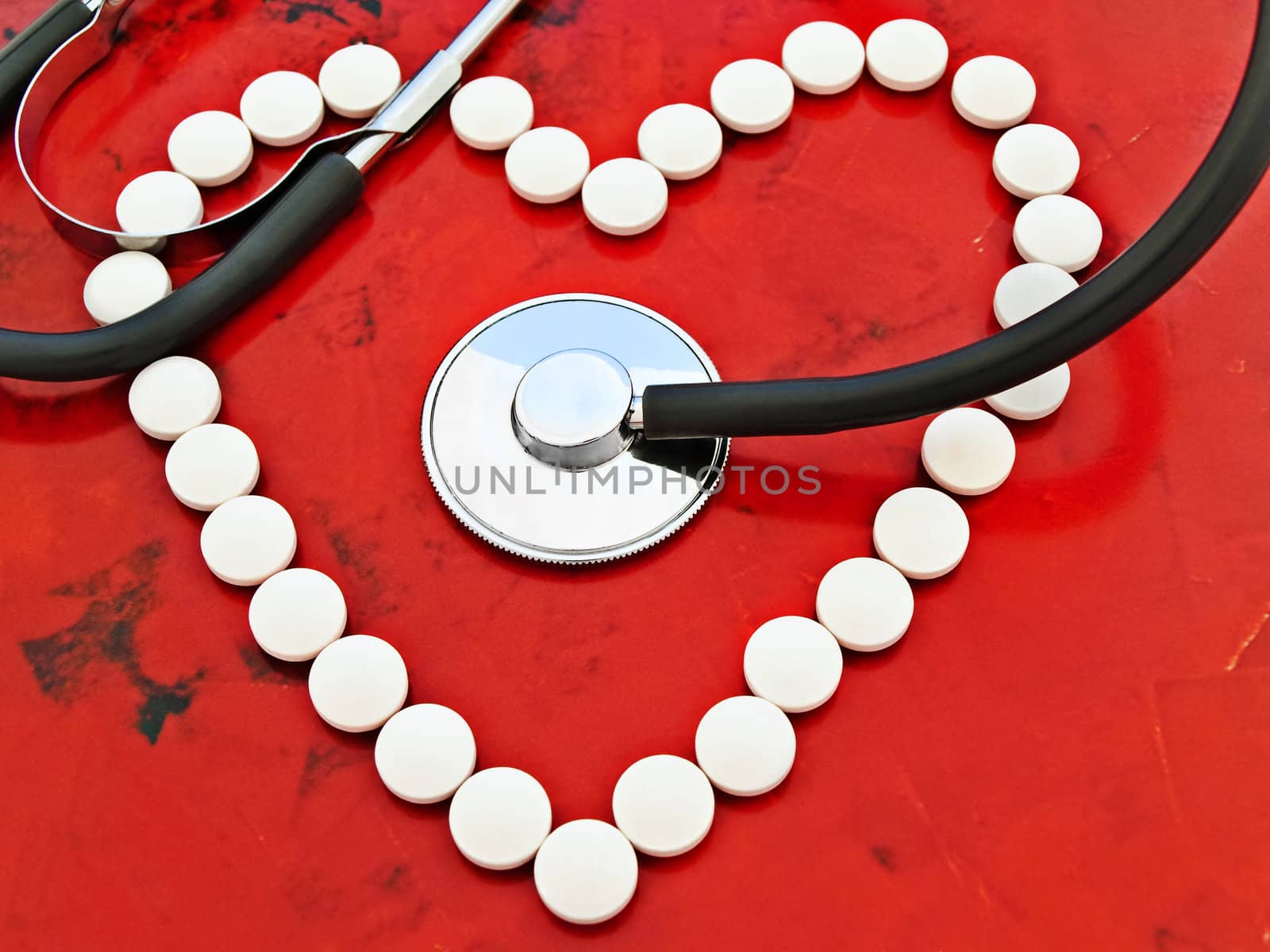 stethoscope and lot of pills over the red background