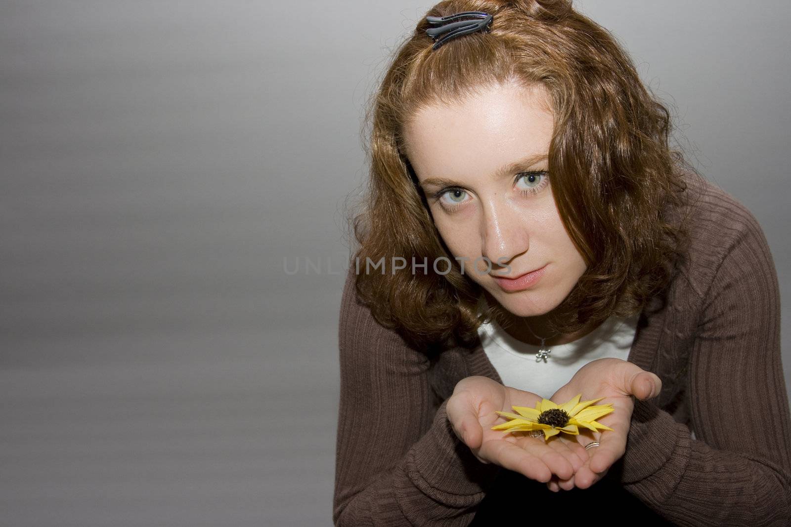 portrait of a beautiful redhaired girl holding a yellow flower in her hands