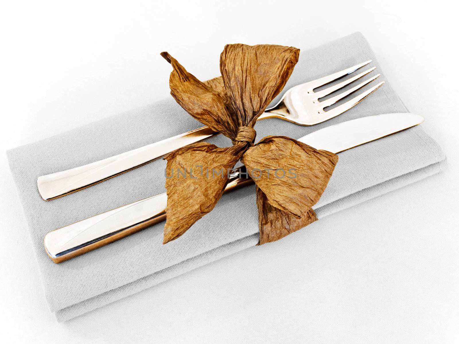 decorated table serving with golden bow in serviette at clear grey