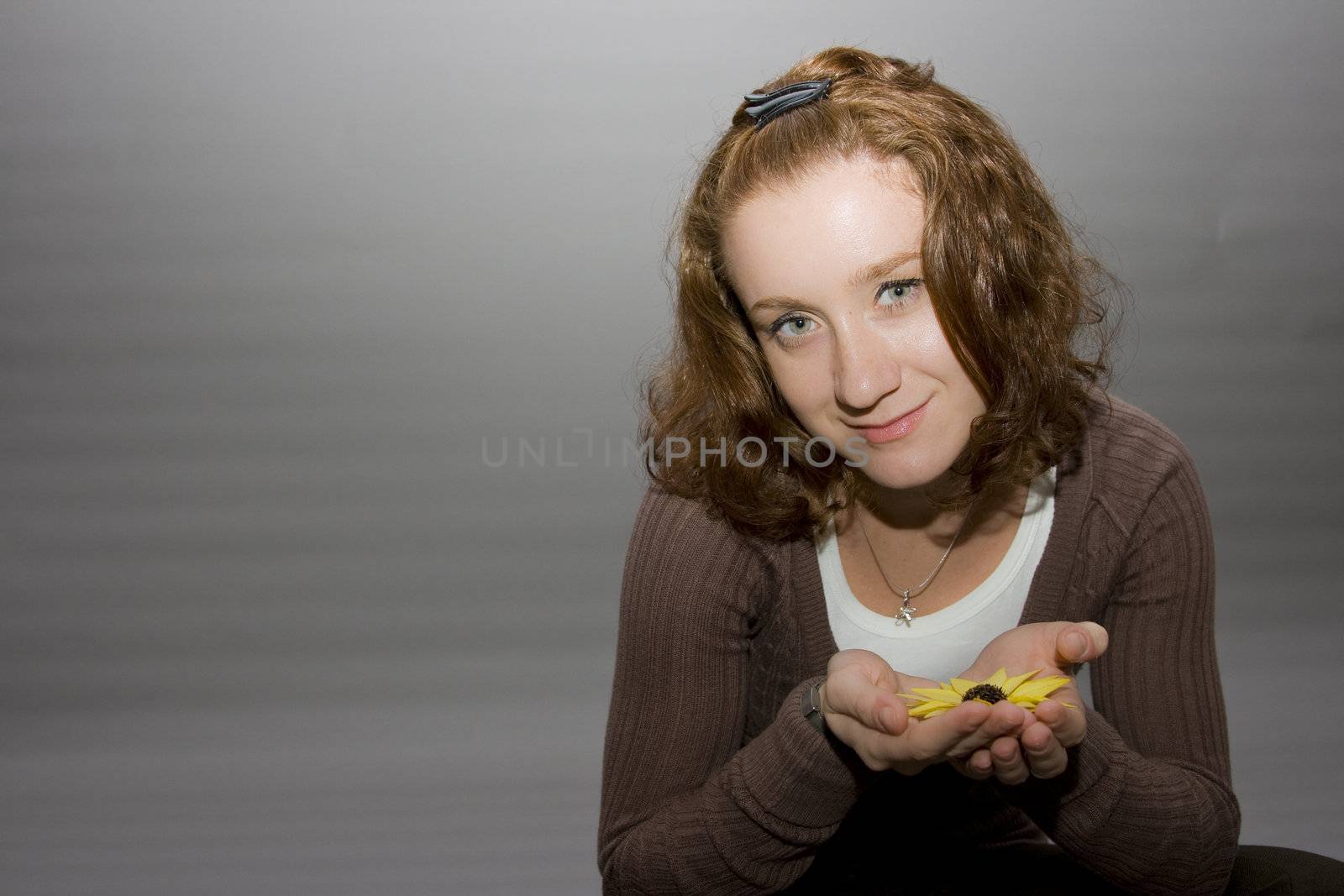 portrait of a beautiful redhaired girl holding a yellow flower in her hands
