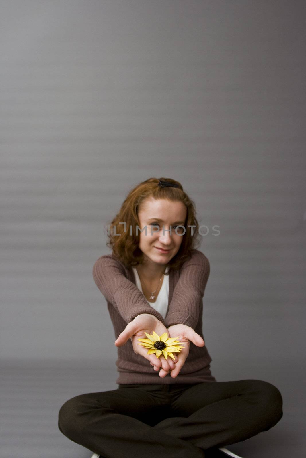 portrait of a beautiful redhaired girl holding a yellow flower in her hands