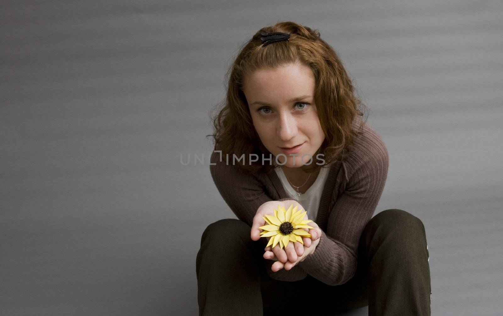 portrait of a beautiful redhaired girl holding a yellow flower in her hands