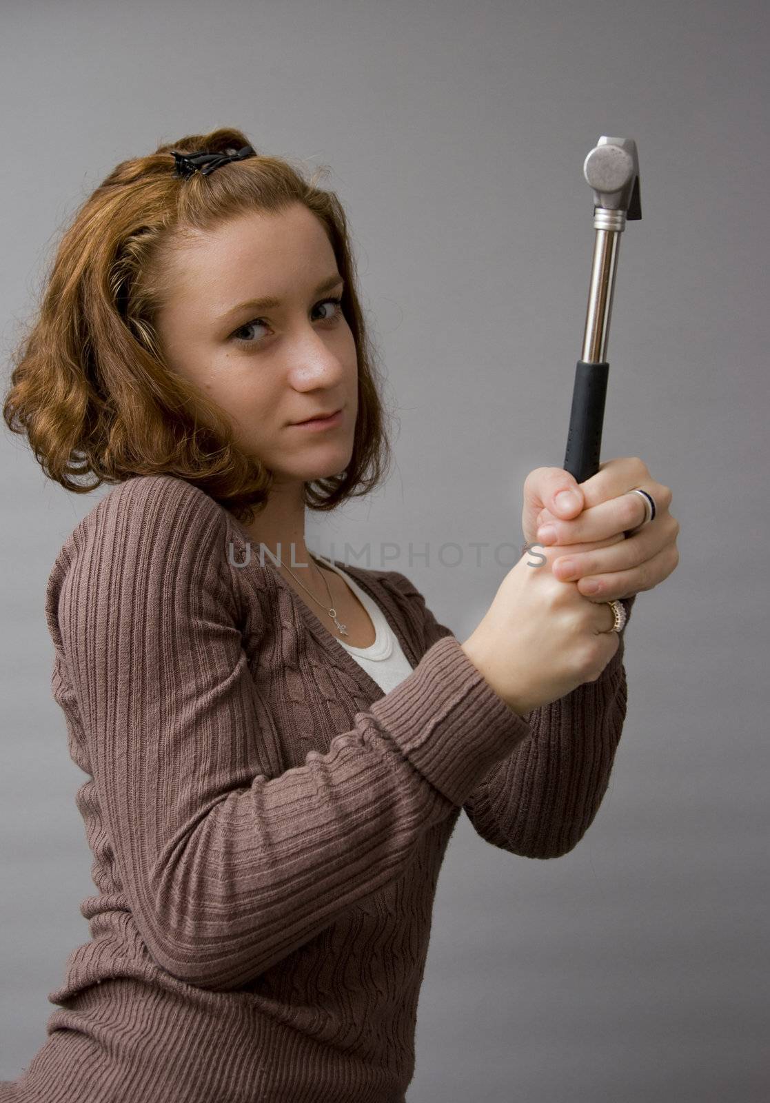 portrait of a beautiful redhaired girl holding a hammer. Be careful!