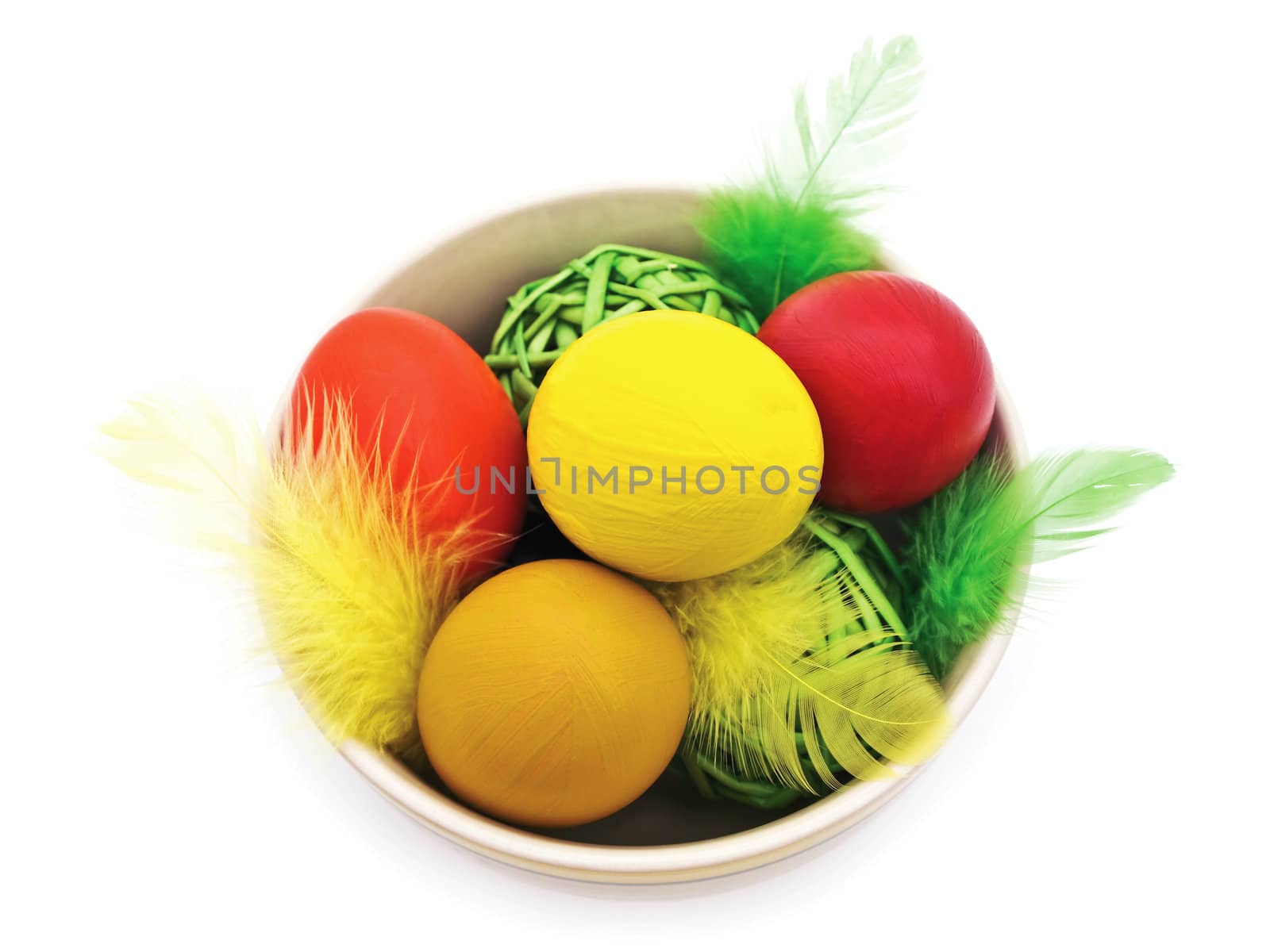 different easter eggs and feathers in the bowl against white background