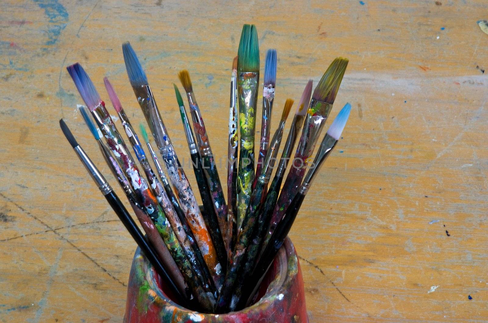 Several artist brushes in a pot, all have been used many times