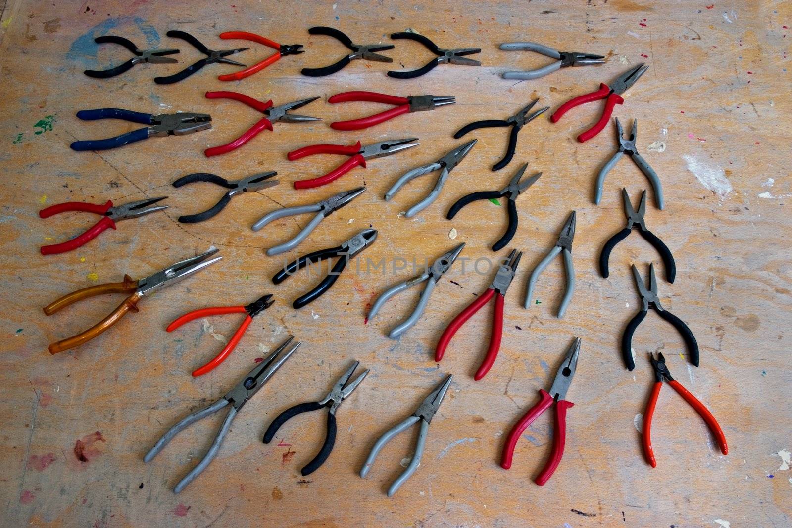 Several shapes and sizes of pliers on a work bench
