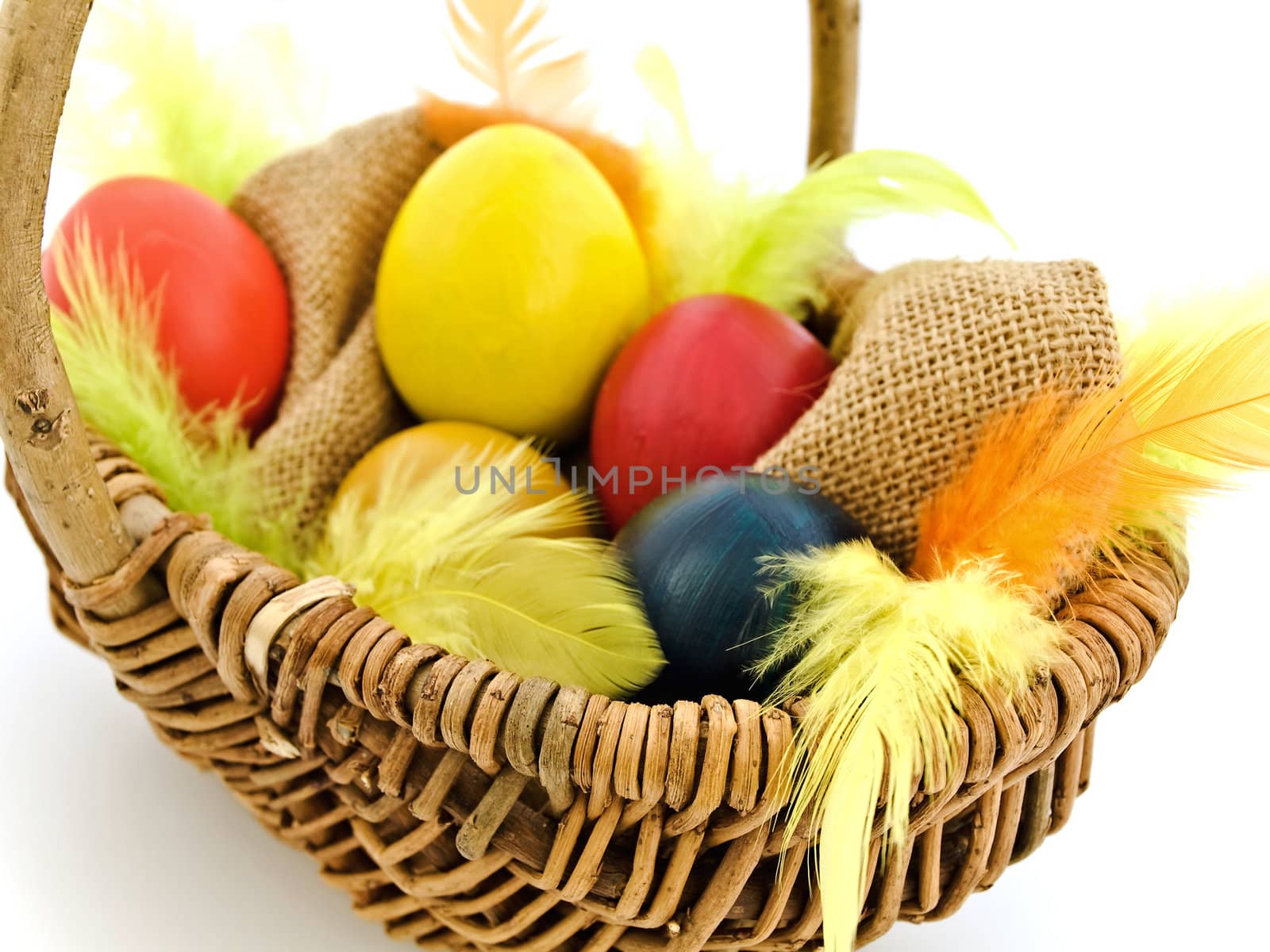 multicolored easter eggs and feathers in the basket