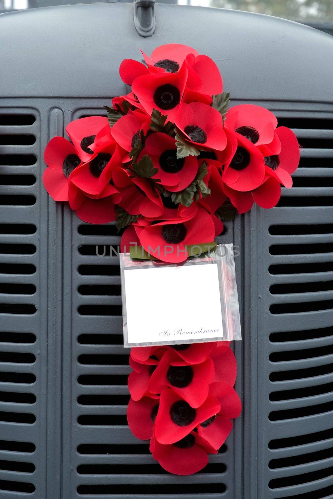 Poppy's in the shape of a cross fastened to the grill of a vintage truck