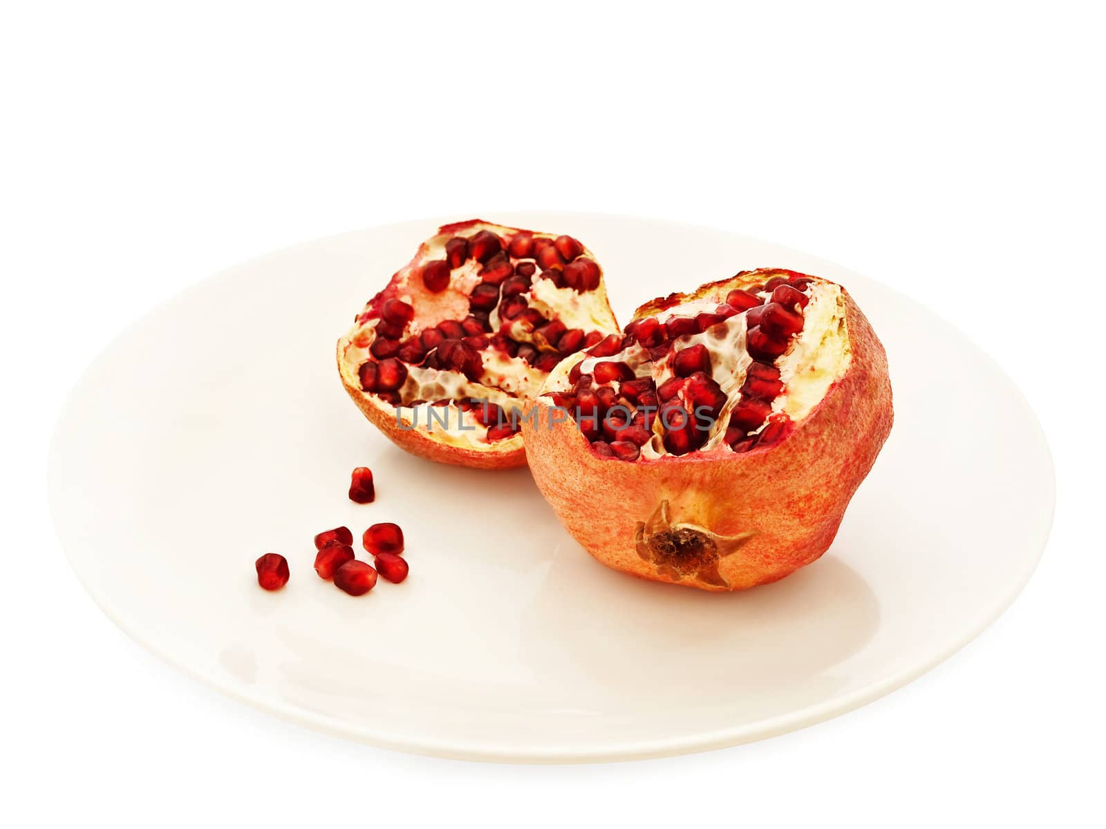 pomegranate in pieces at plate over white background