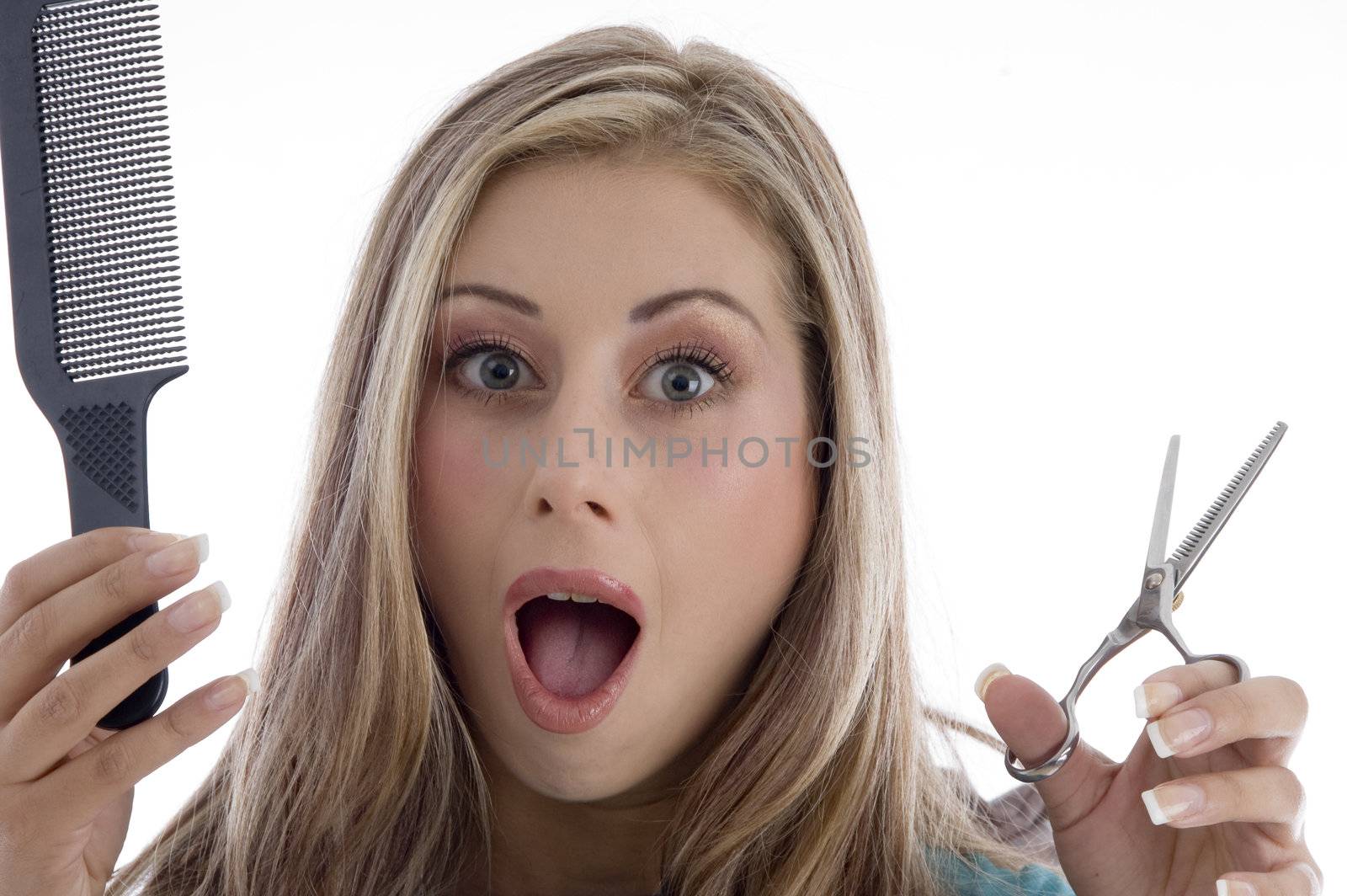 surprised woman holding scissor and comb on an isolated background