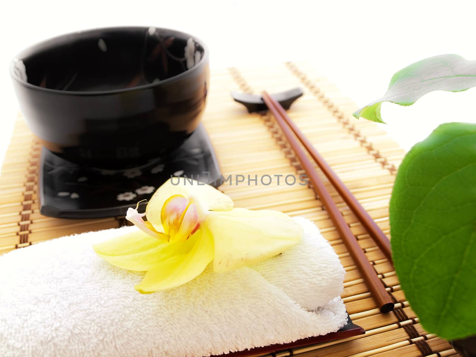 oriental style table serving with bowl, orchid and green leaves 