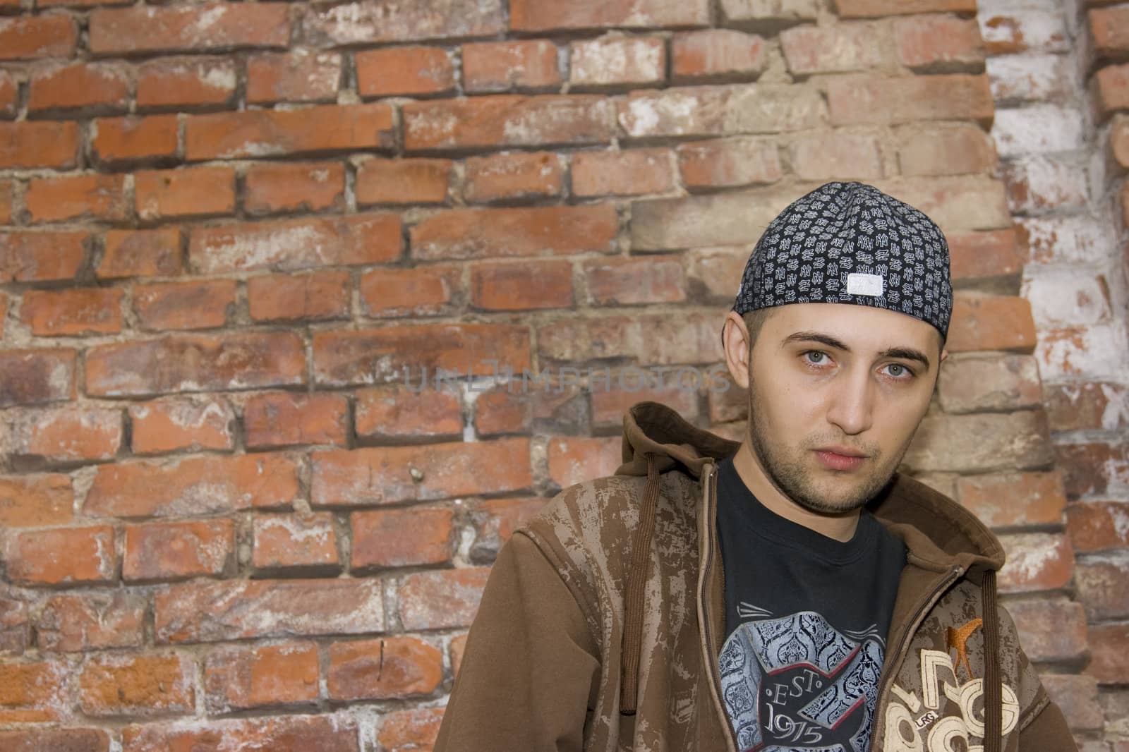 Rapper boy posing at a brick wall, urban scene