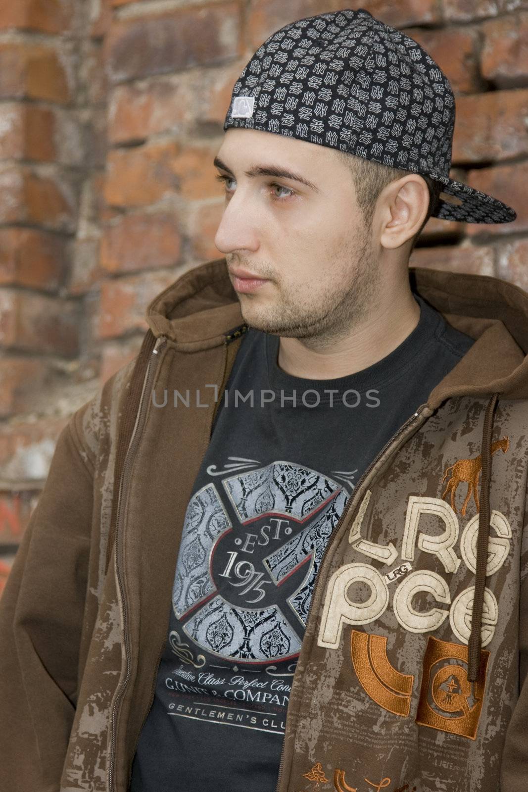 Rapper boy posing at a brick wall, urban scene