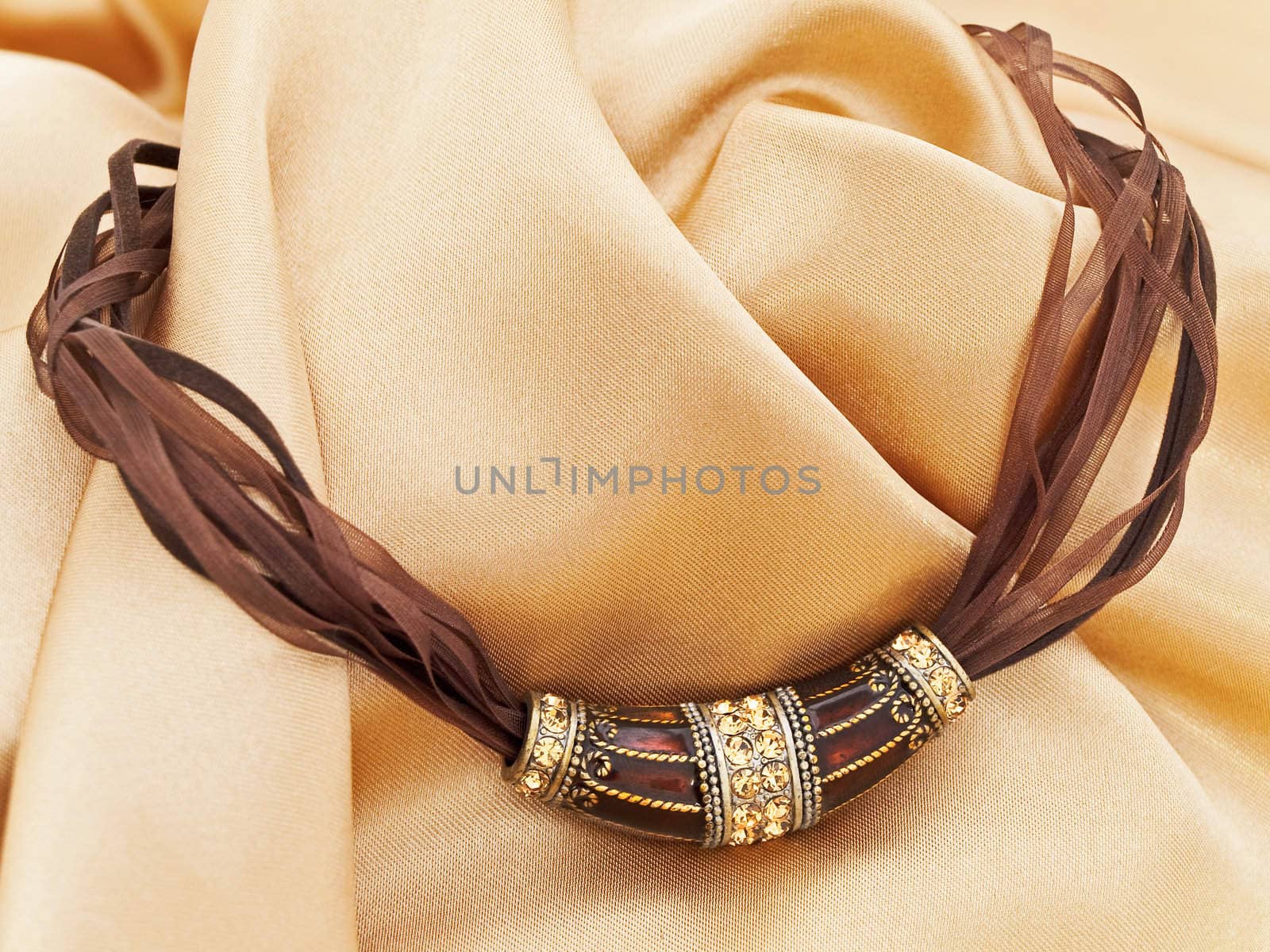  fashion brown necklace with gems over golden textile background