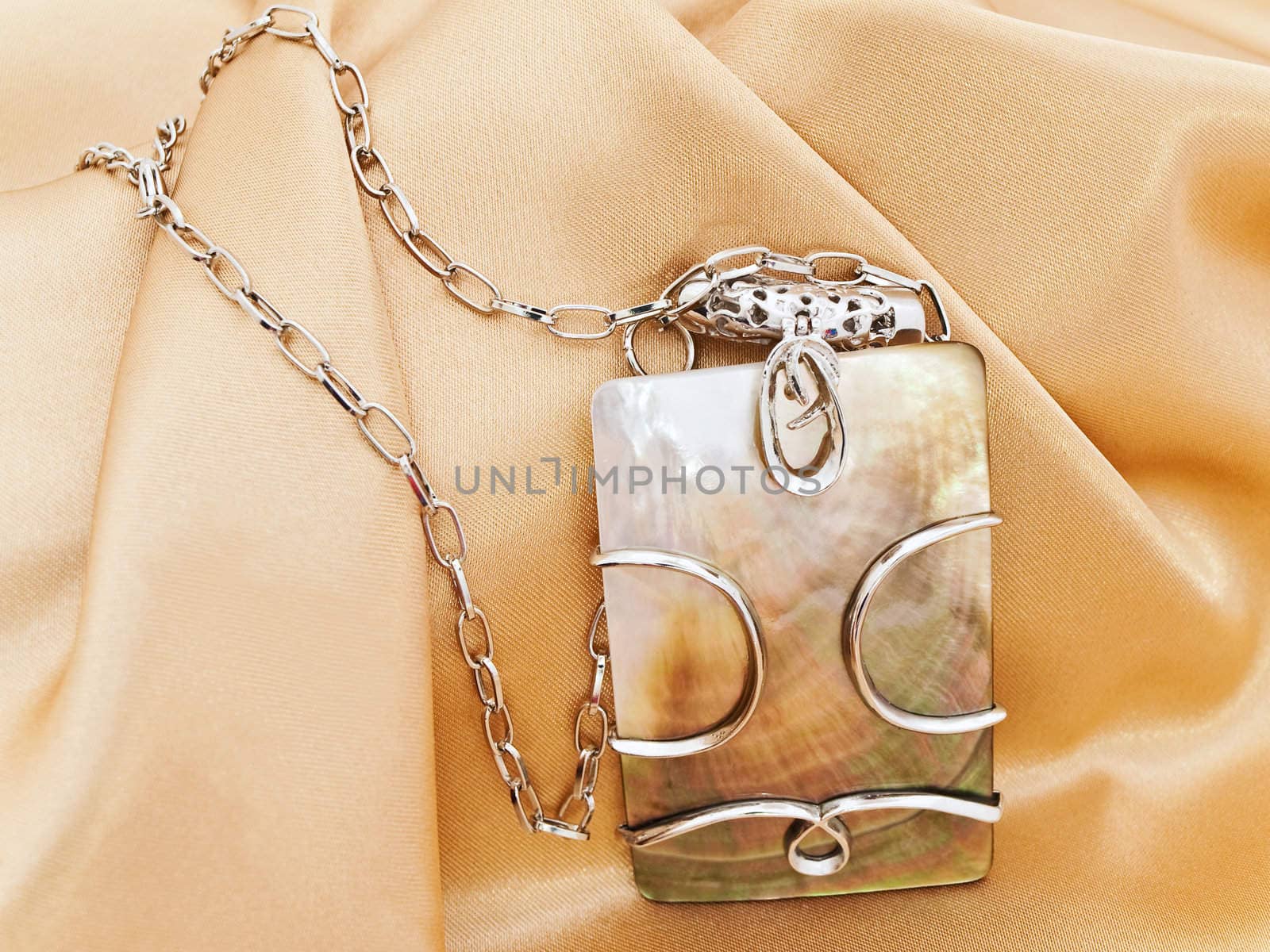  fashion necklace with metal decoration over golden textile background