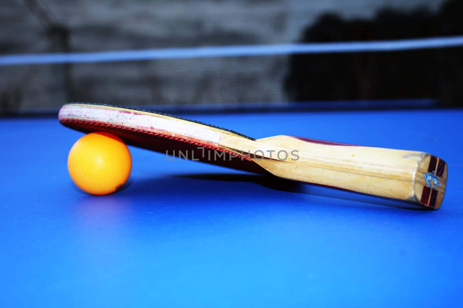 the tennis bat and a ball on a tennis table.