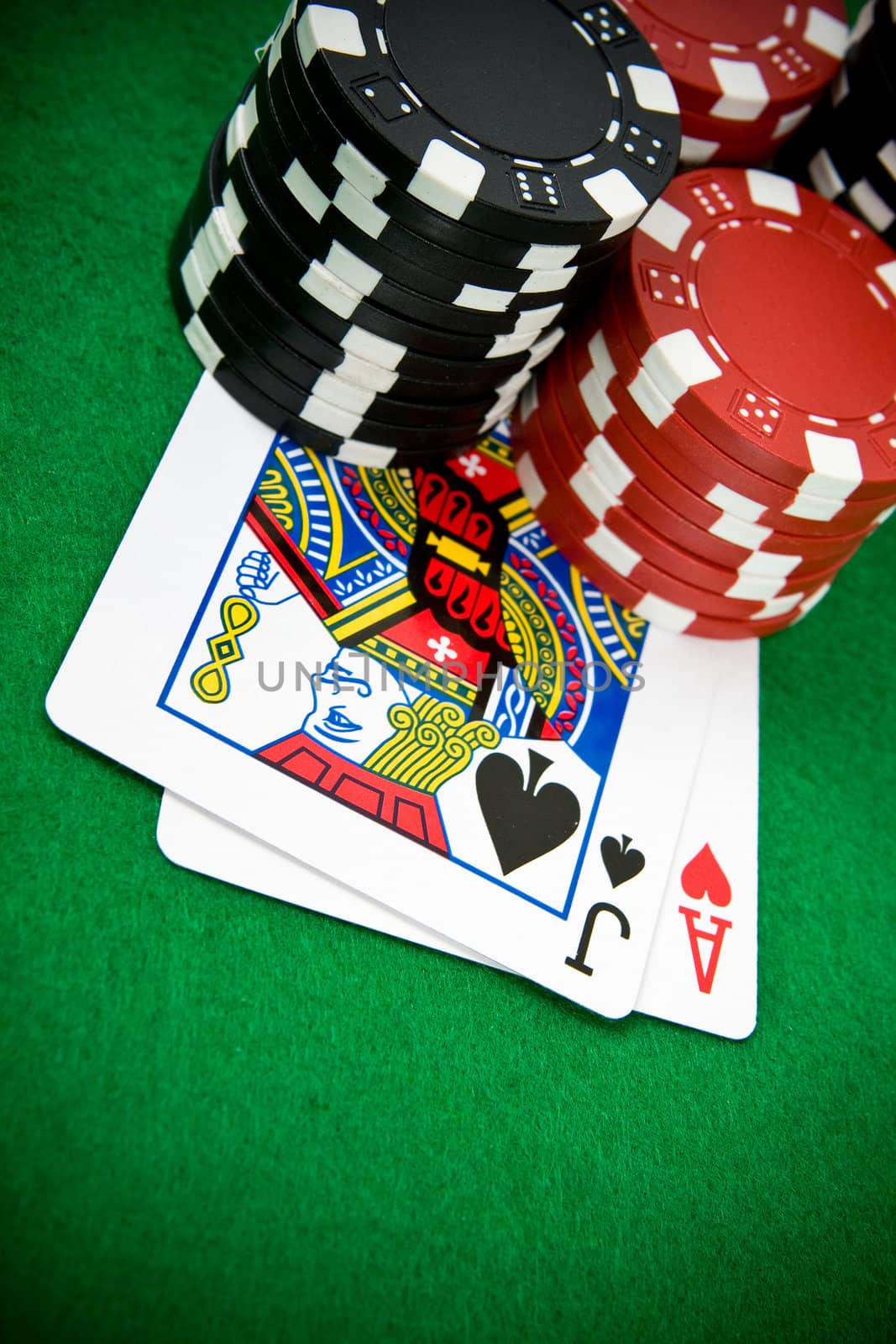 Ace of hearts and black jack with black and red poker chips in the background.