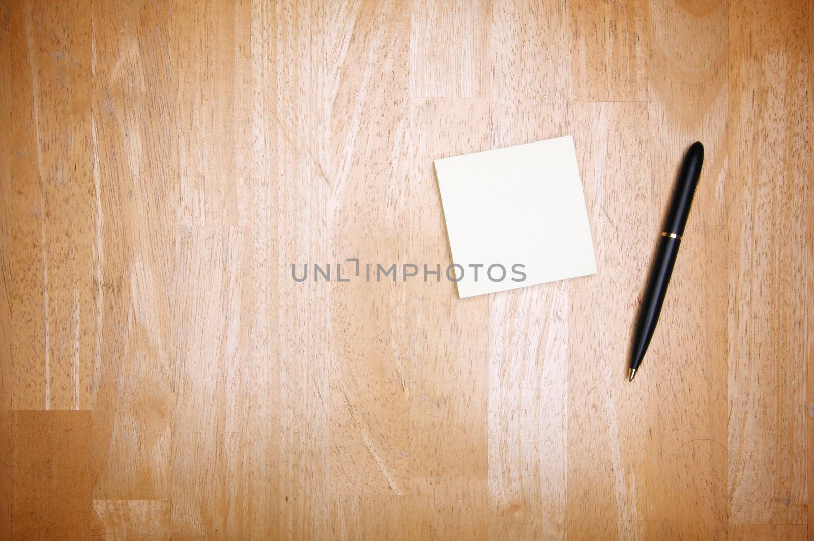Pen and Post It Notes Pad Against a Wood Background