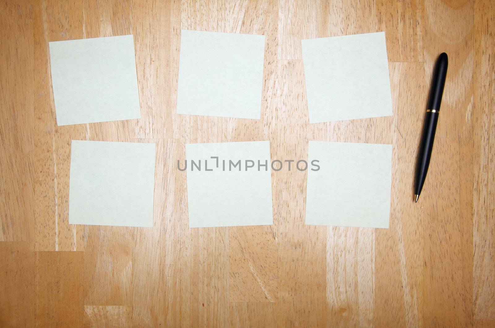 Pen and Post It Notes Pad Against a Wood Background