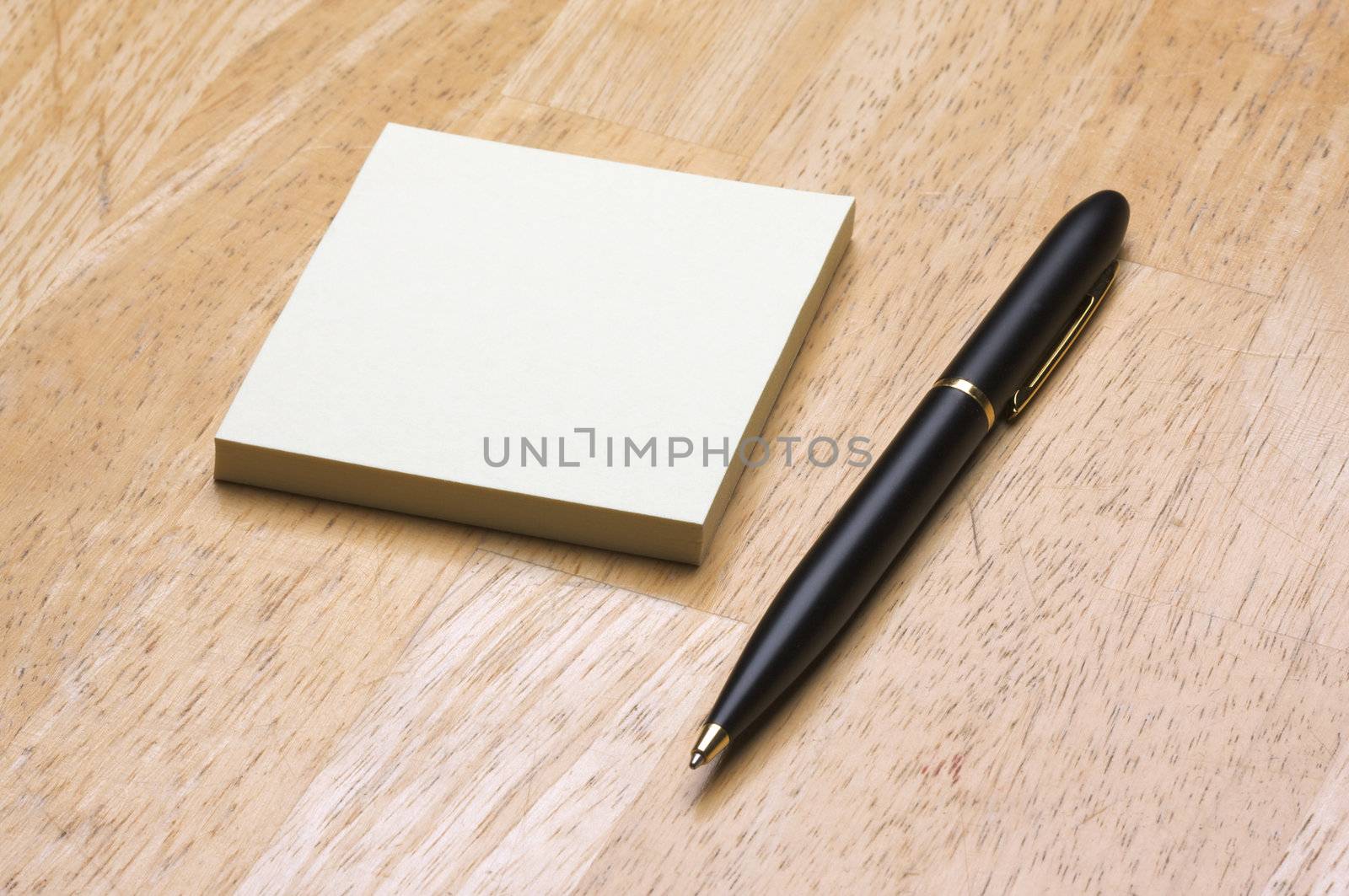 Pen and Post It Notes Pad Against a Wood Background