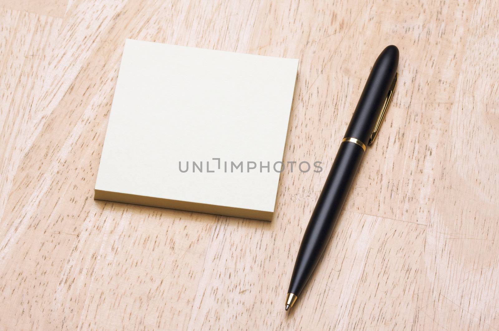 Pen and Post It Notes Pad Against a Wood Background