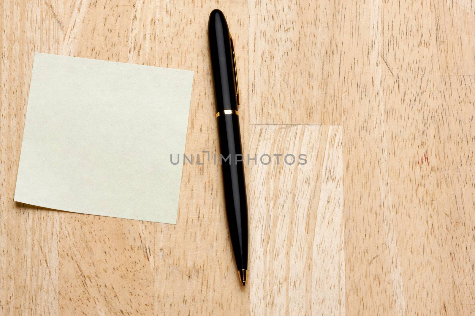 Pen and Post It Notes Pad Against a Wood Background