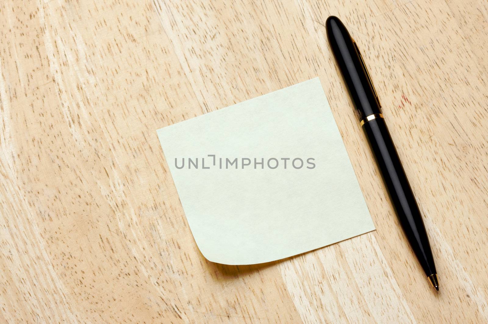 Pen and Post It Notes Pad Against a Wood Background