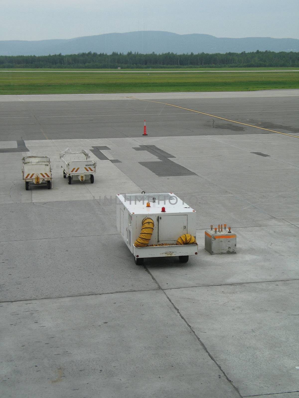 empty airplane gate with small trucks by mmm