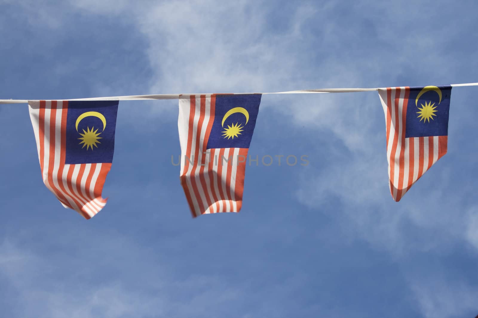 Three small Malaysia flag over blue sky background.