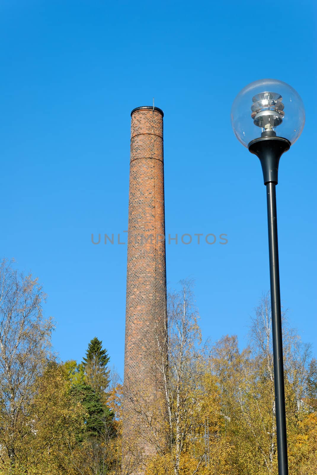 Old brick factory chimney and a glass street light in autumn setting
