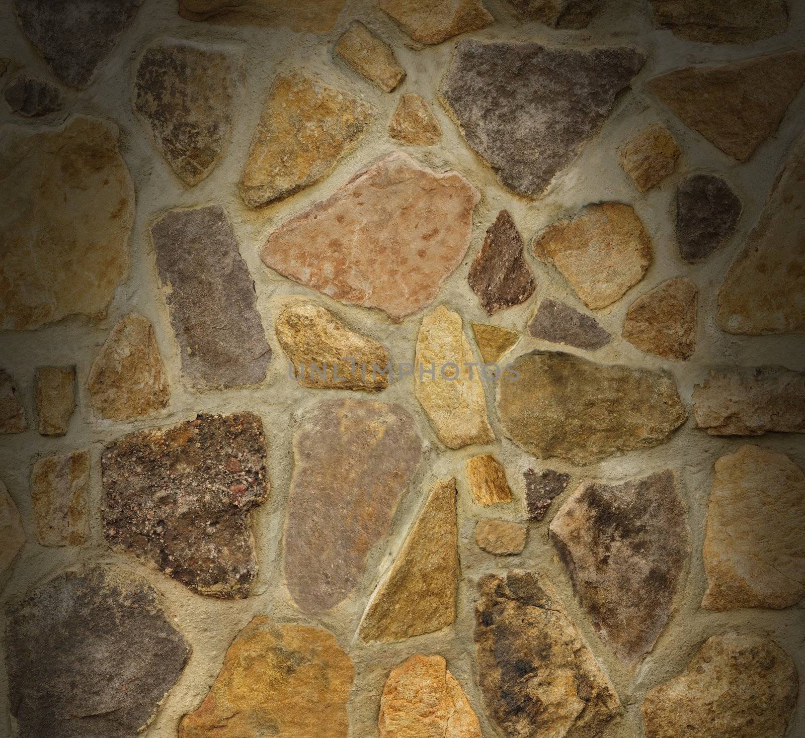 Masonry wall with irregular shaped stones dramatically lit from above