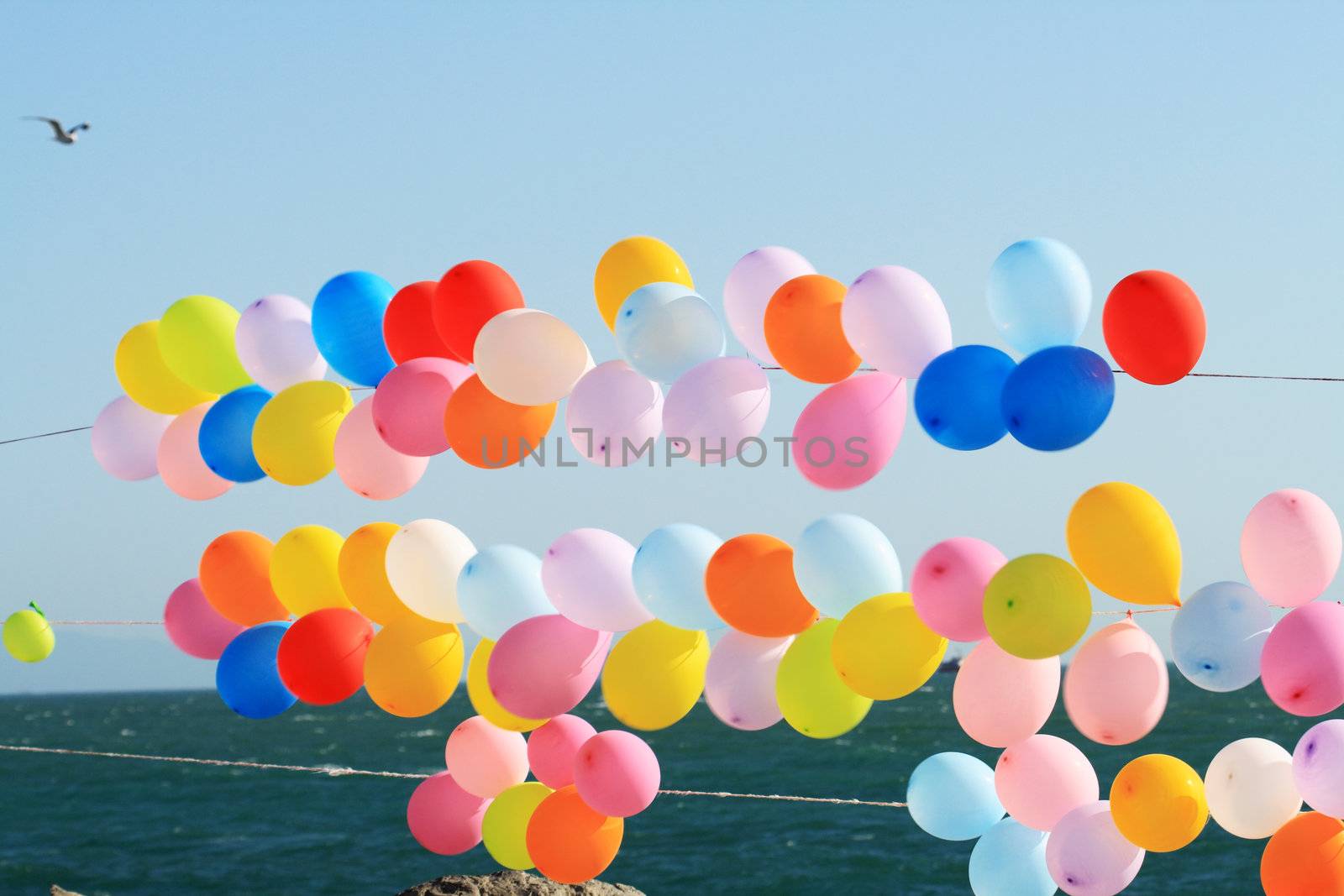 Lots of colorful balloons on background with blue sky and sea