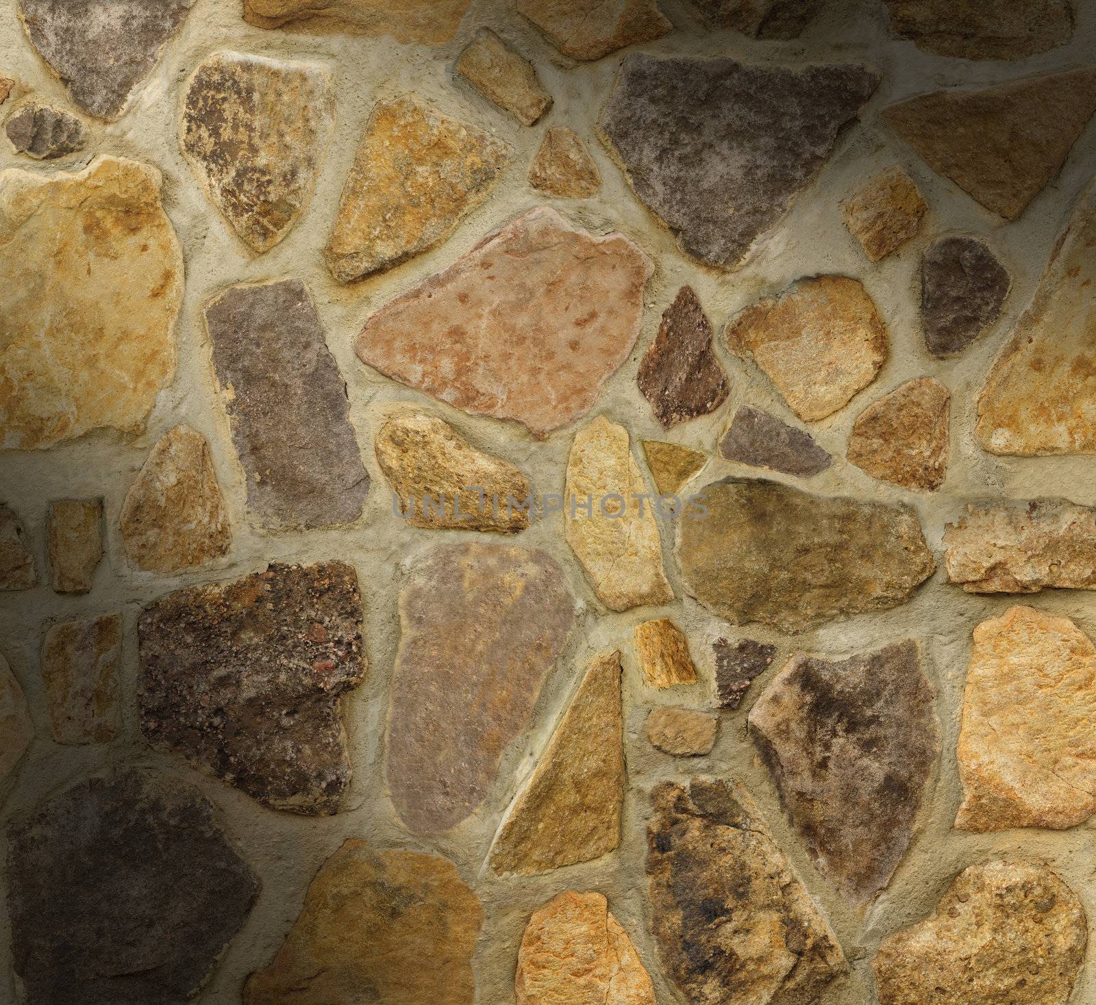 Masonry wall with irregular shaped stones dramatically lit diagonally