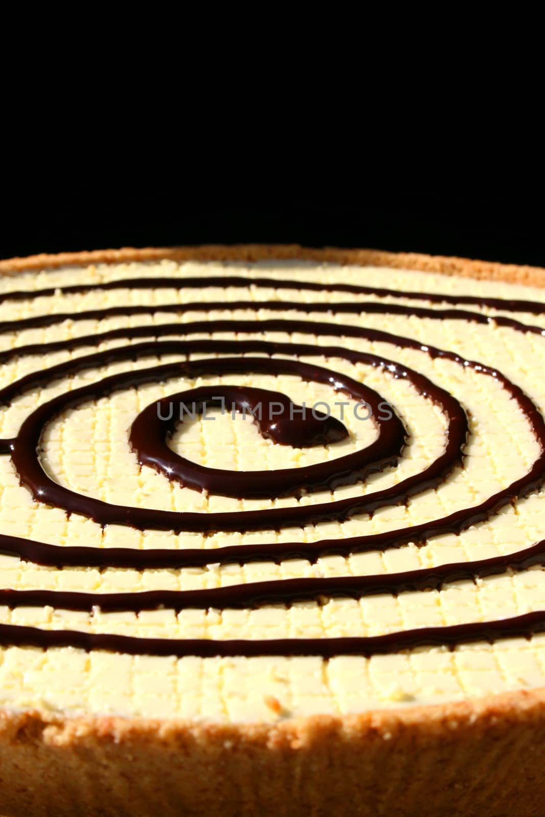 Close up of a big cake with chocolate swirl on top.
