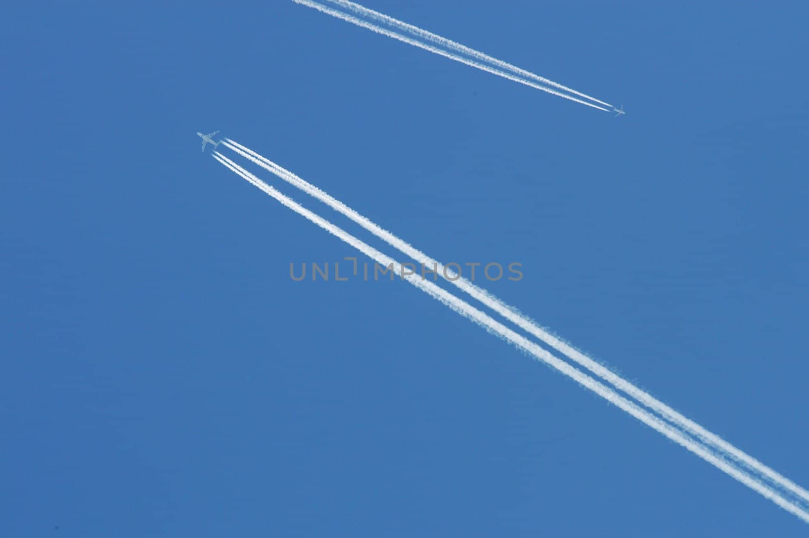 Flying airoplanes on the blue sky leaving white lines behind