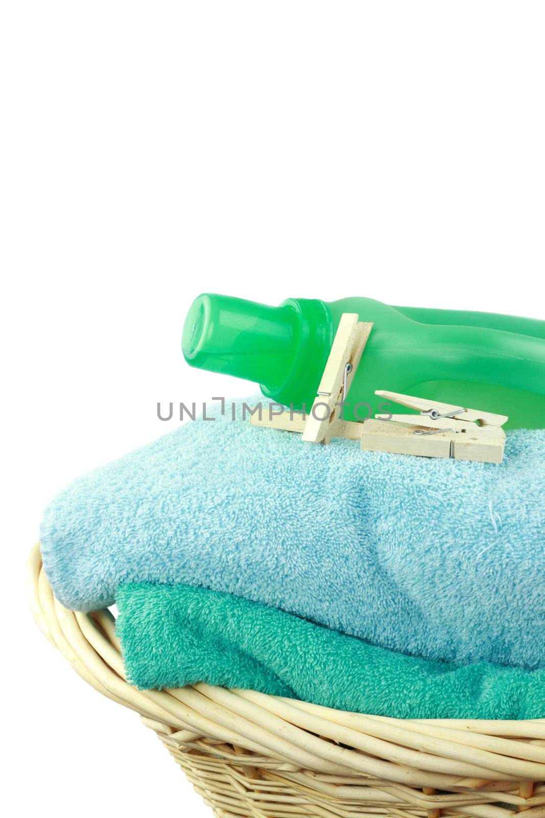 Laundry basket with fresh towels, laundry soap and clothespins isolated on white.

