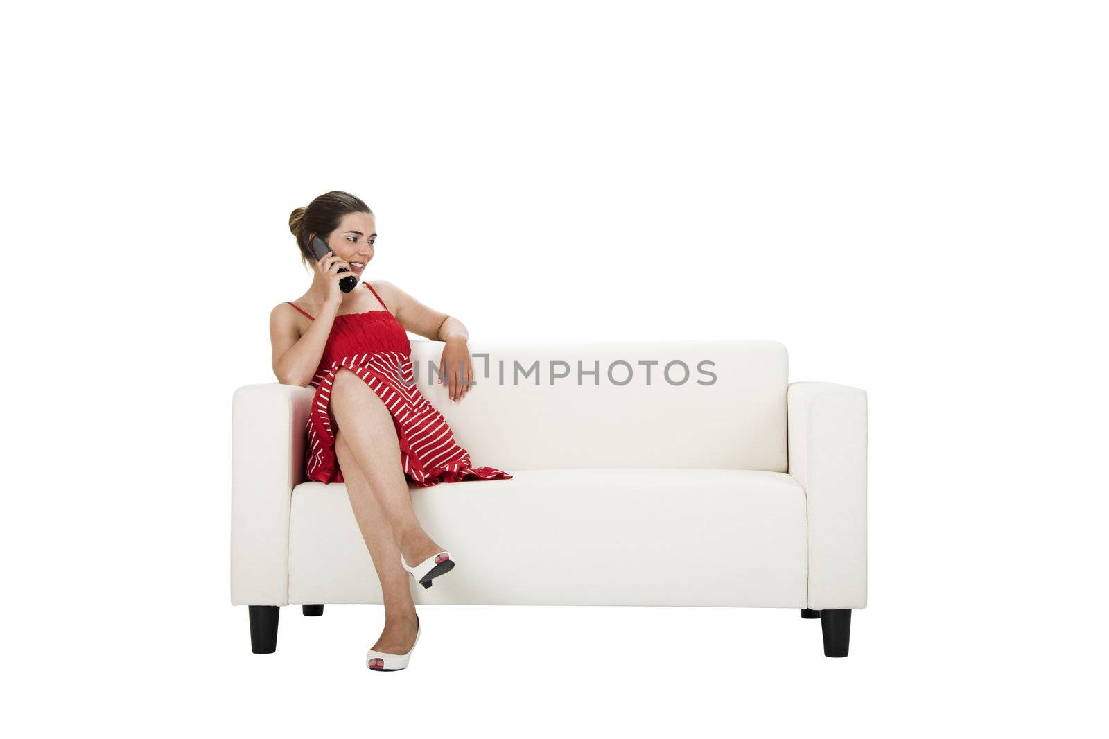 Beautiful woman seated on a couch talking on the cellphone with a happy face