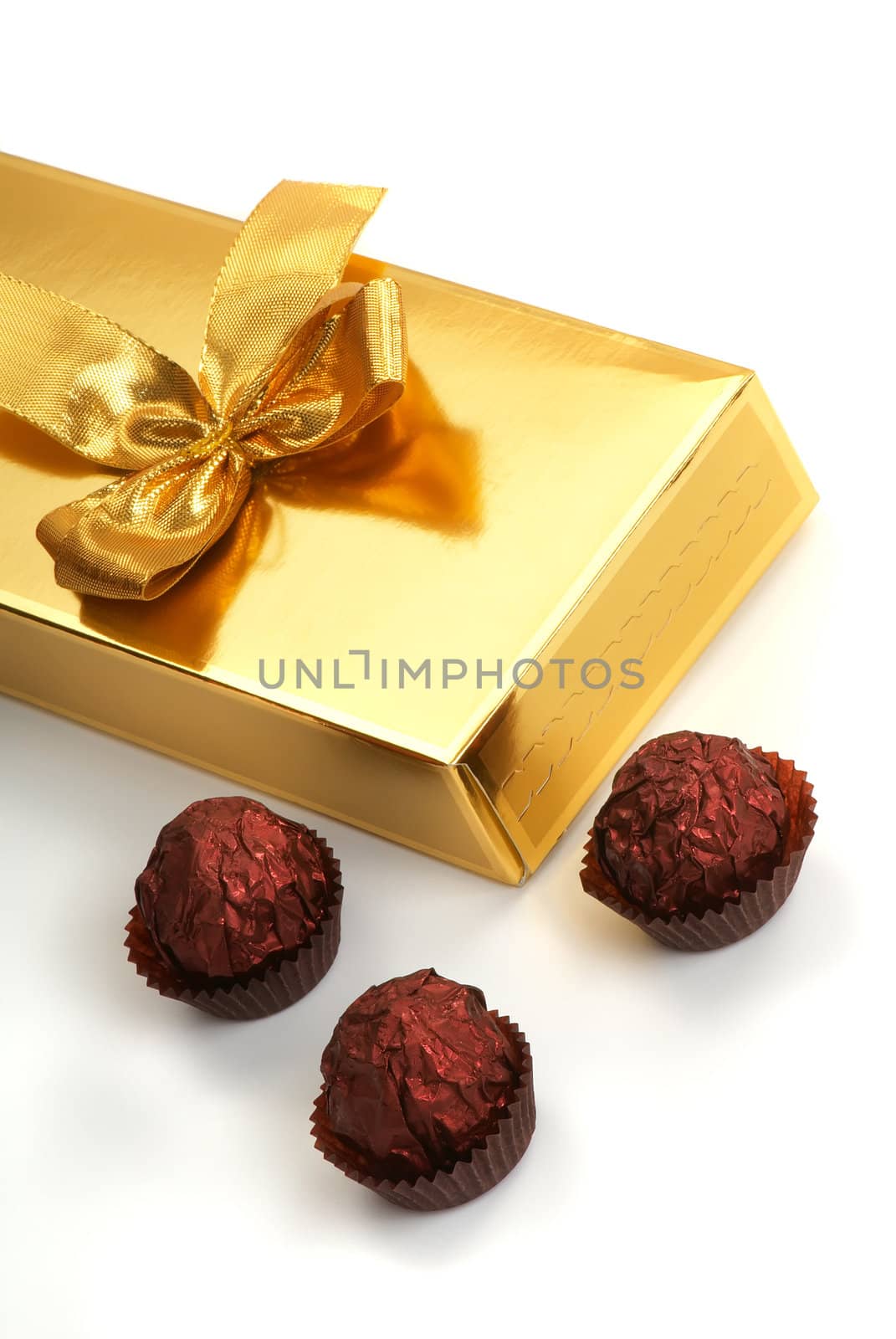 A gold boxed gift with gold ribbon and sweet.
