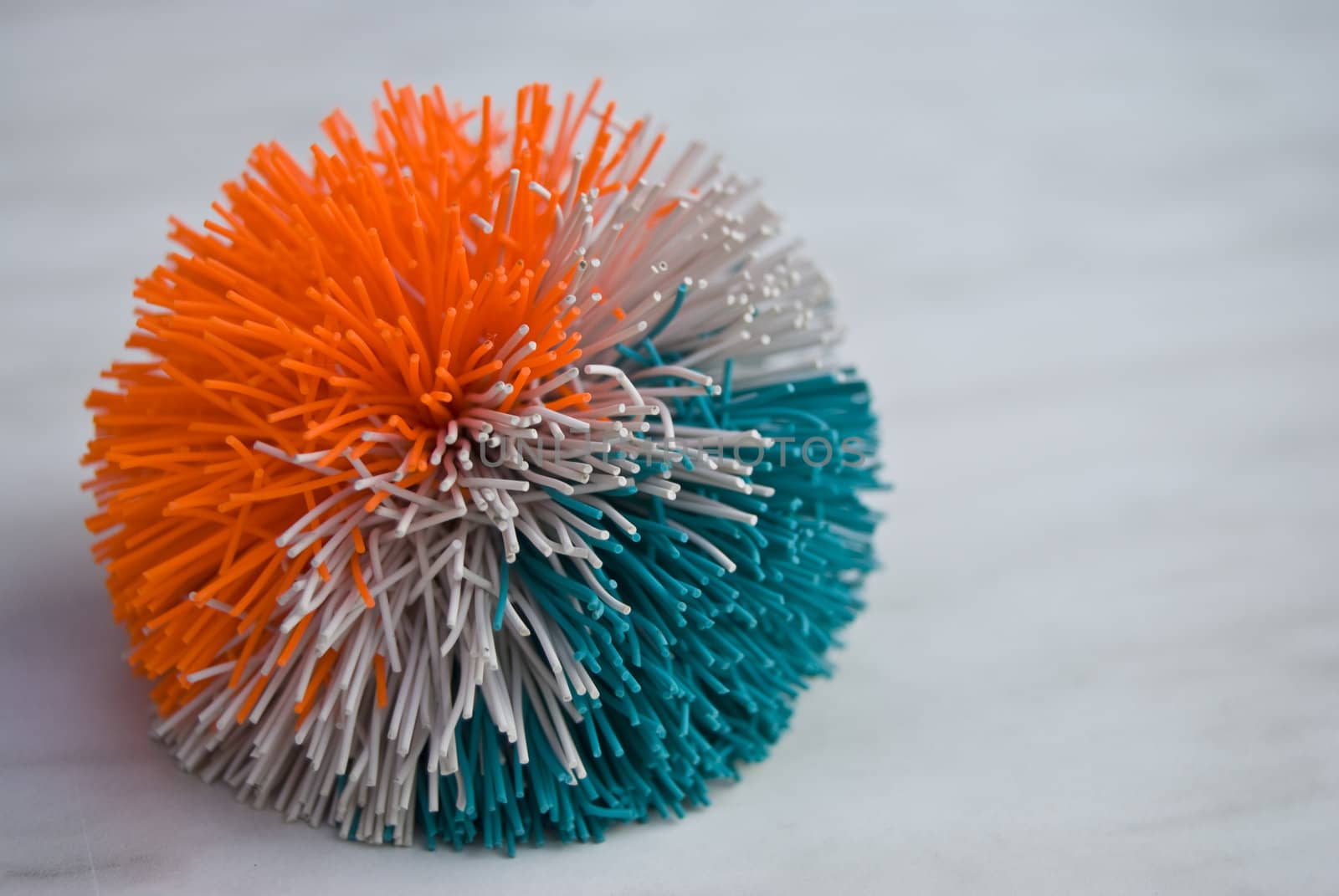 fuzzy ball in orange, grey and blue on a table