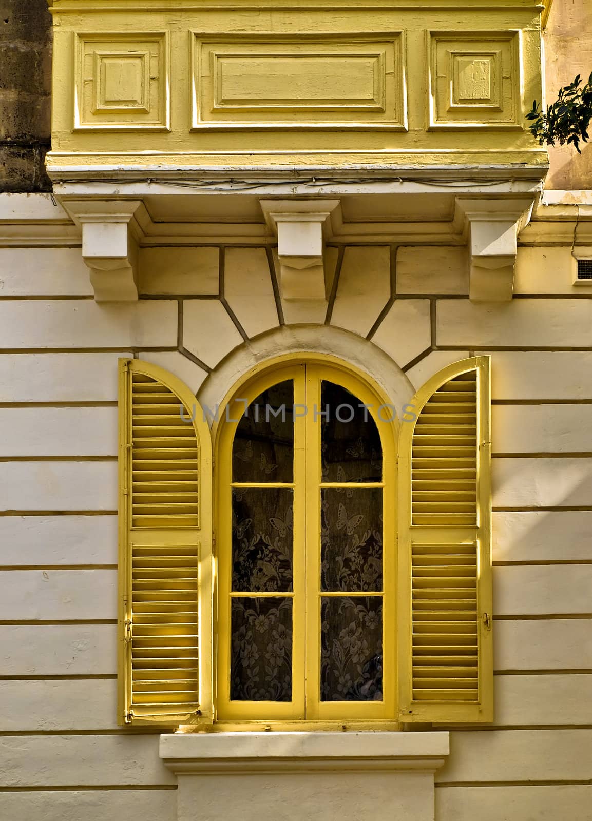 Yellow arched and louvered window of a house in Malta 