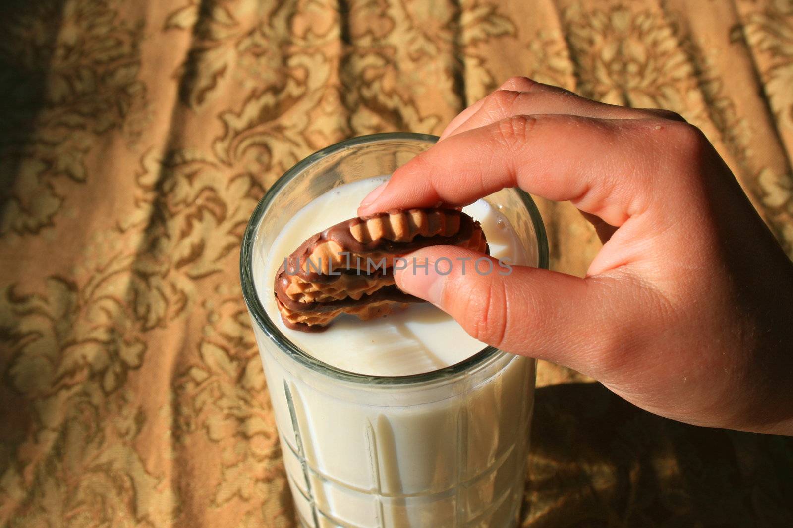 Close up of a cookie and a glass of milk.
