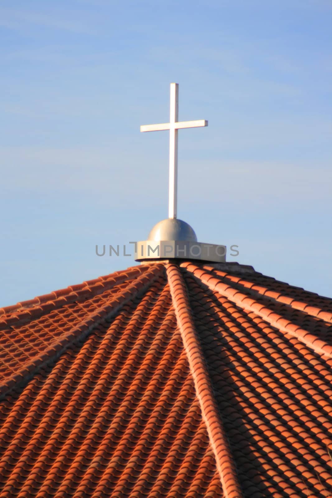 Cross on top of a church over blue sky.
