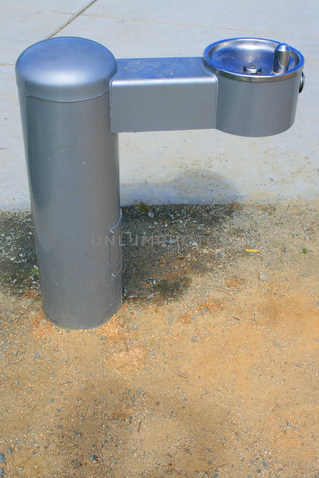 Drinking fountain on a sidewalk in a park.
