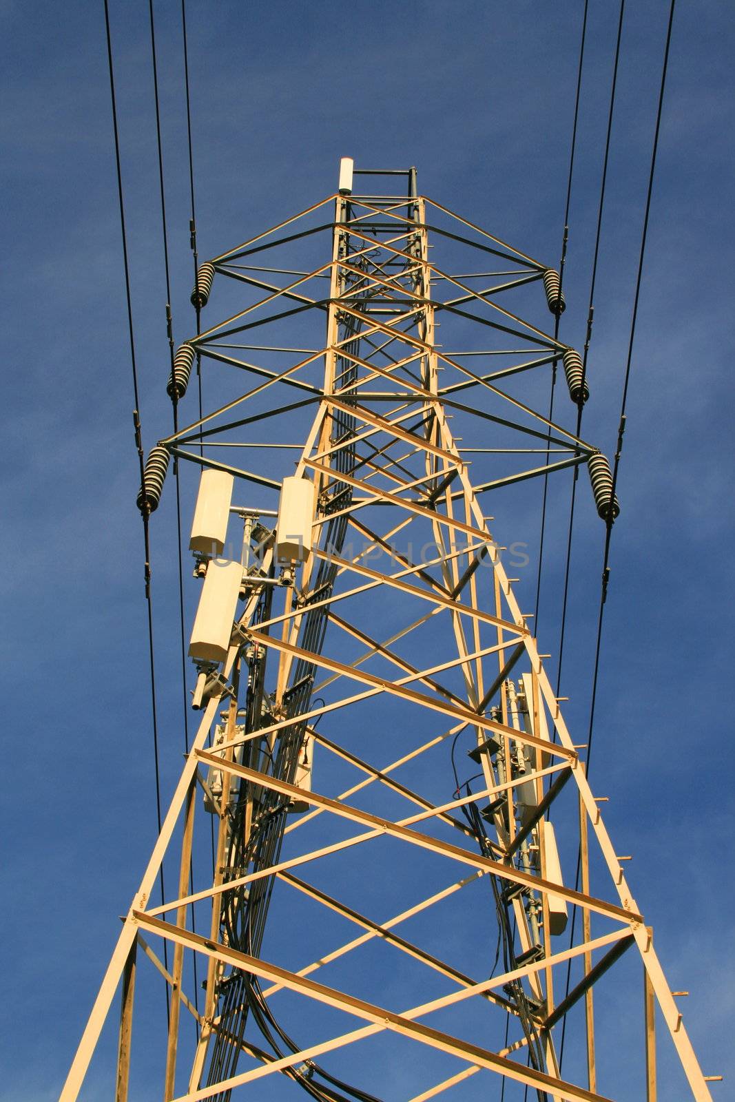 Top of the electricity pylon over blue sky.
